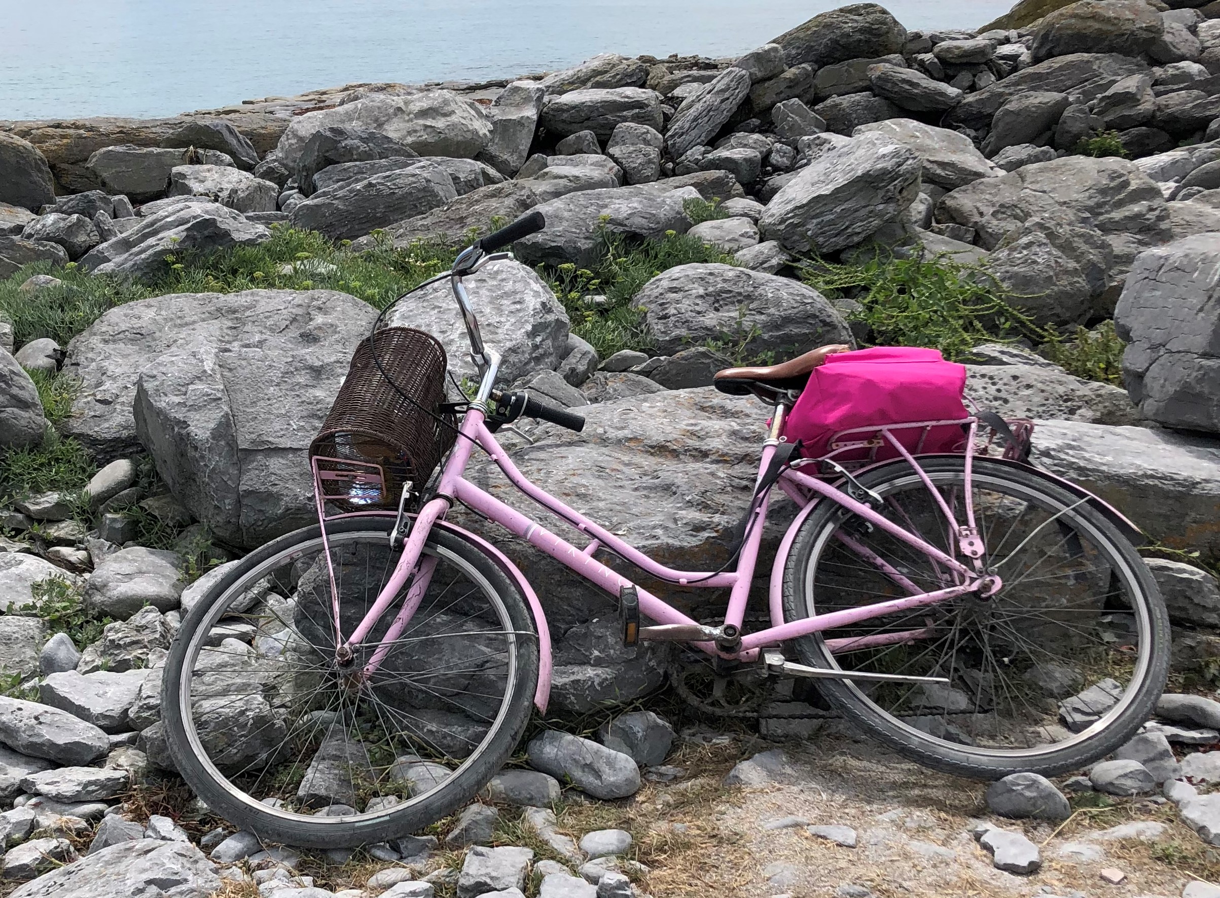 pink bike leaning up against large stones